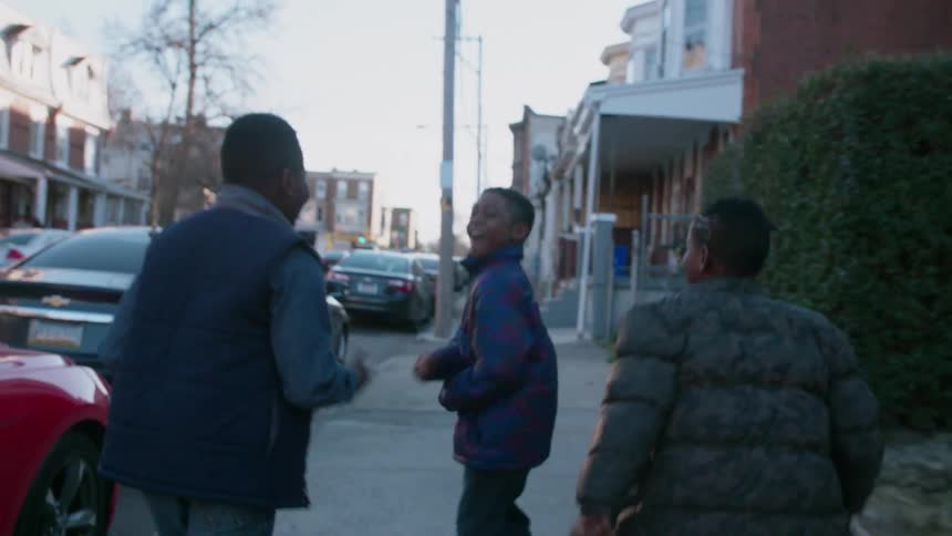 Three kids run down the sidewalk