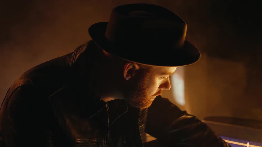A man crouches next to tvs in a smoky room