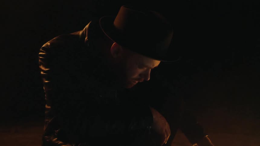 A man is looking at a monitor sitting on the ground in a dark room