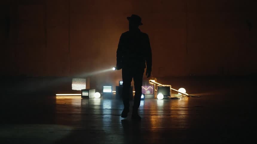 A man shines his flashlight as he walks by monitors