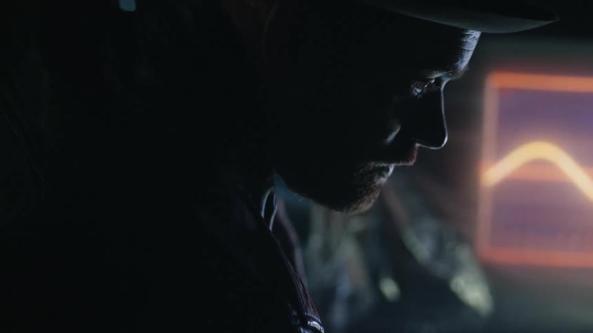 A man is standing in the dark by the televisions