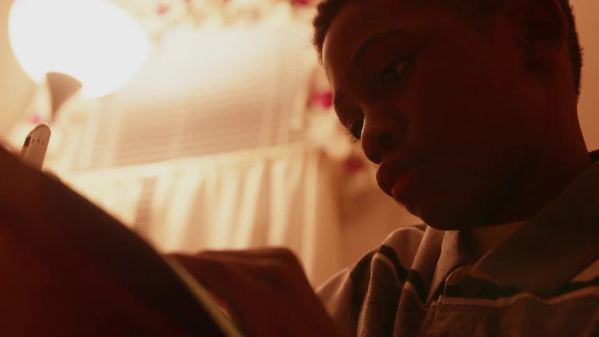 A boy is writing in a notebook
