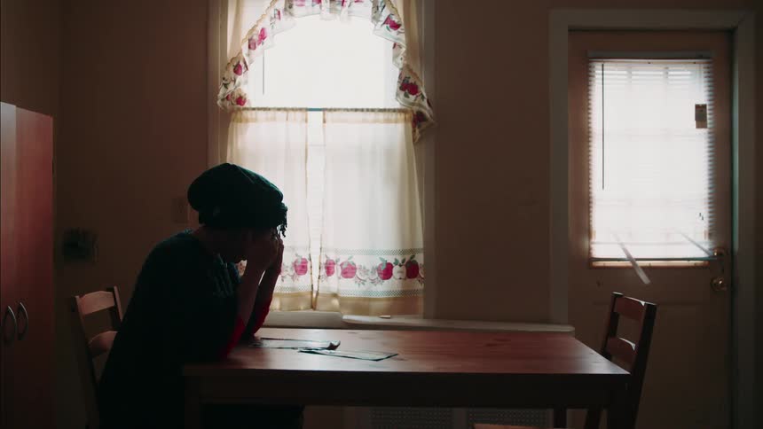 A woman is sitting and thinking at table in home during the day
