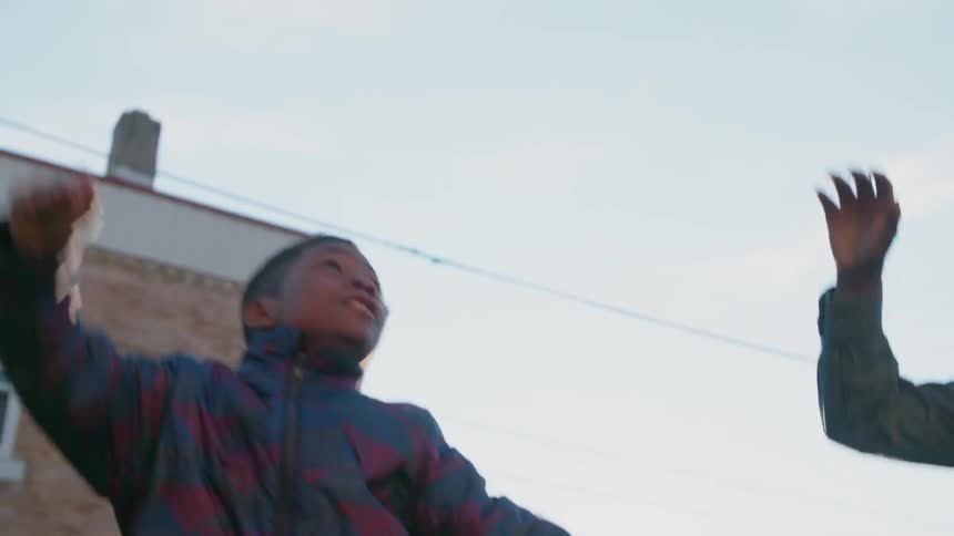 A boy is tossing a basketball into the air outside in winter