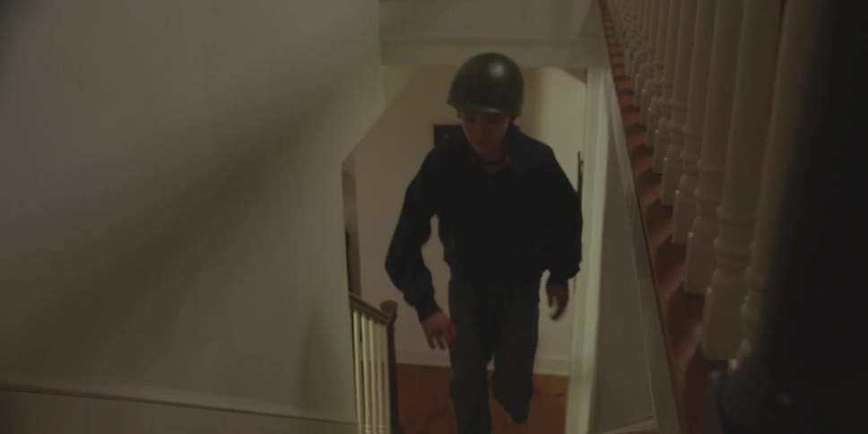 A boy wearing a helmet running up the stairs in a house