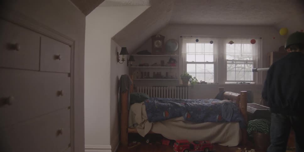 A boy enters a bedroom and kneels in front of a chest