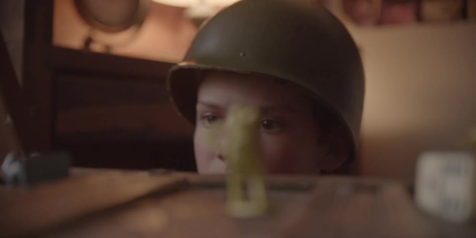 A boy wears an army helmet and plays with army figures