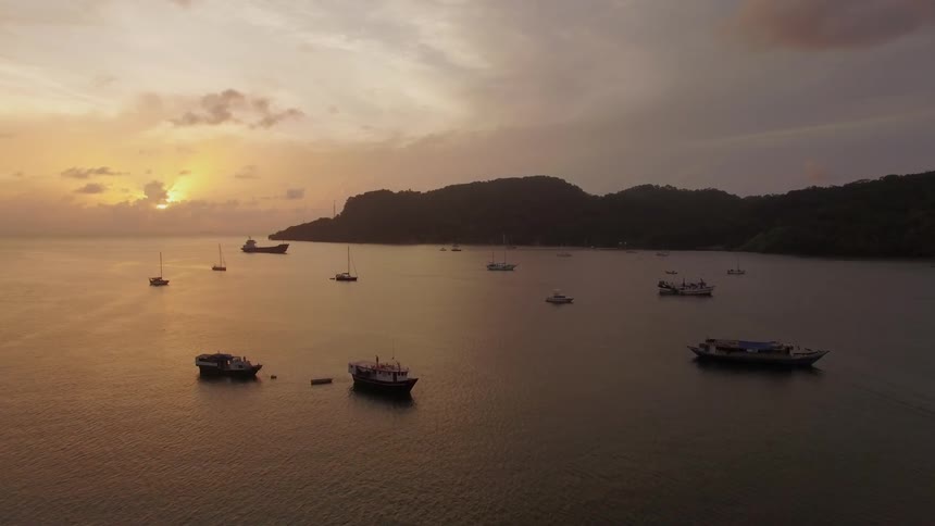 Boats float peacefully near the ocean coast at sunset