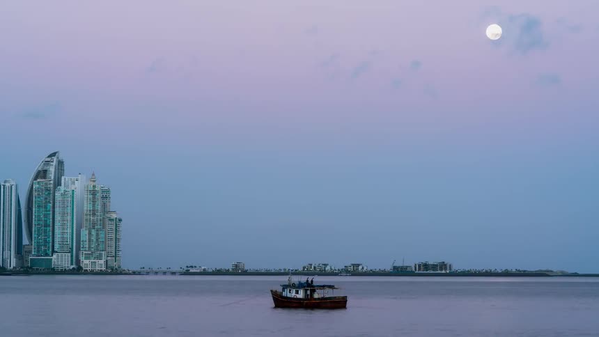 A boat floats on a city river at sunrise