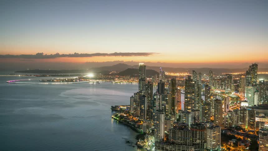 A city on a harbor is teaming with lights and traffic at dusk