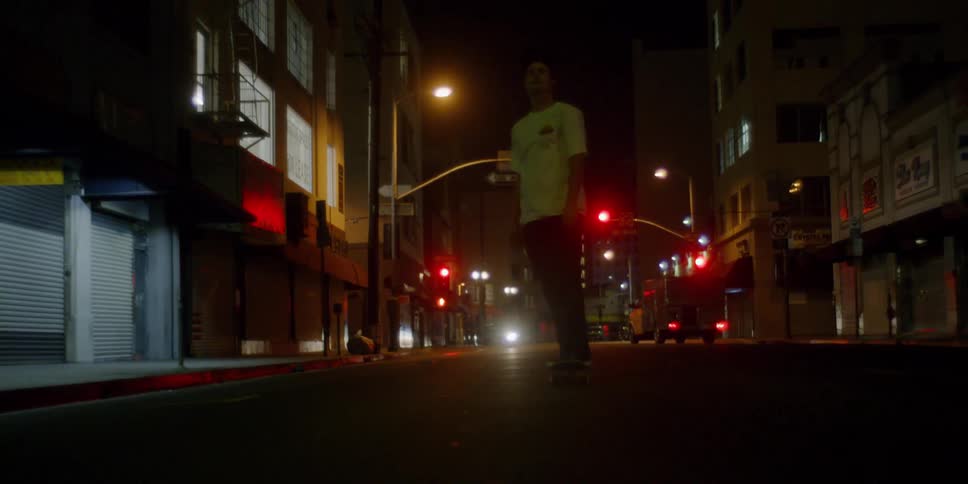 A teenager is skateboarding on a city street at night