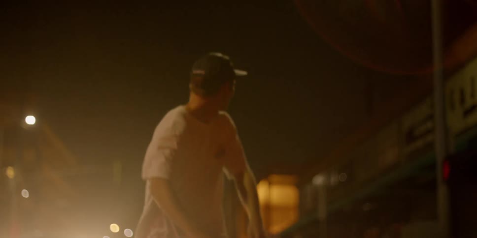 A skateboarder rides down a city street at night
