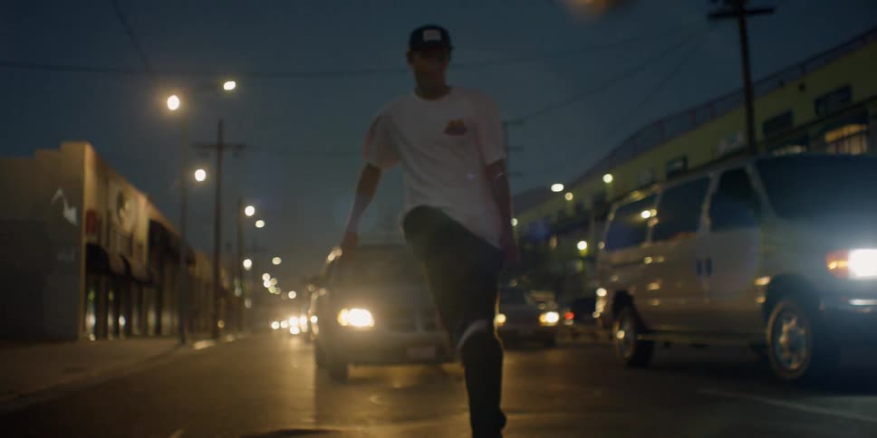 A man is riding his skateboard in traffic at night