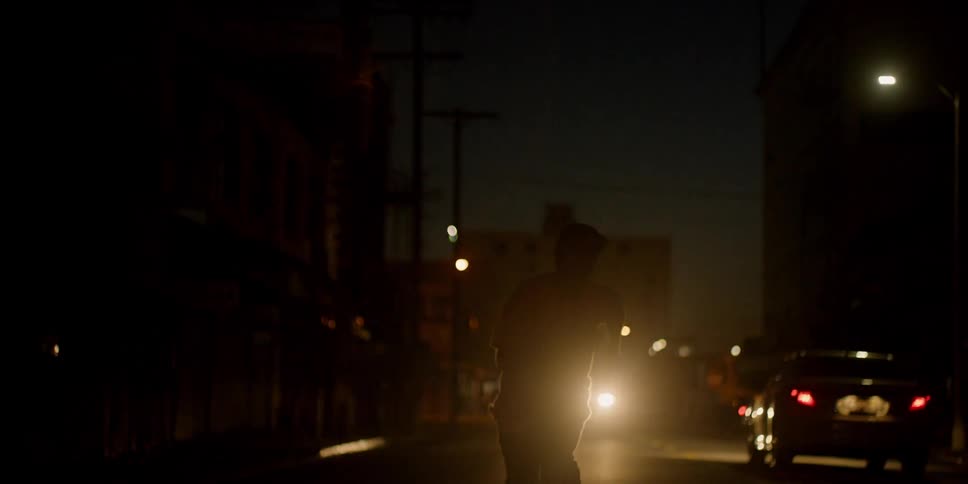 A man rides his skateboard down the dark street