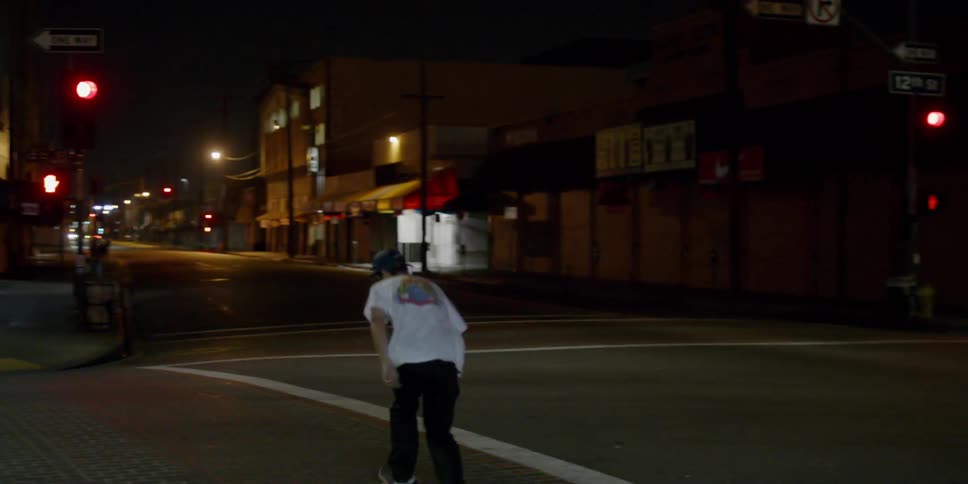 A man looks down at the floor and rides off on a skateboard