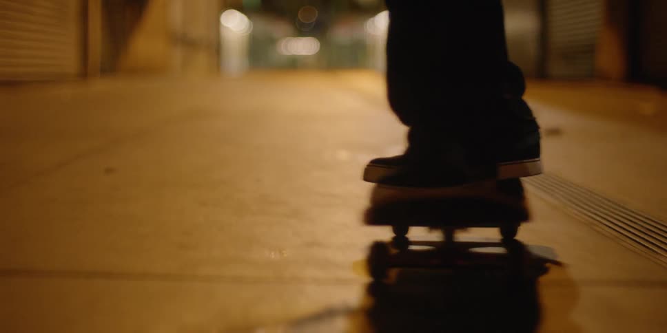 A teenager is riding a skateboard in a city alley at night