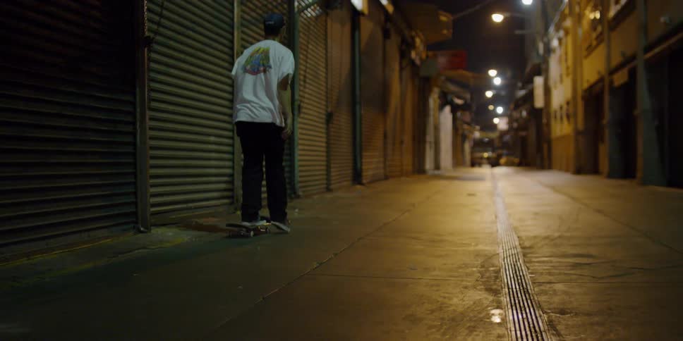 A man pushes off and rides a skateboard on a city side street