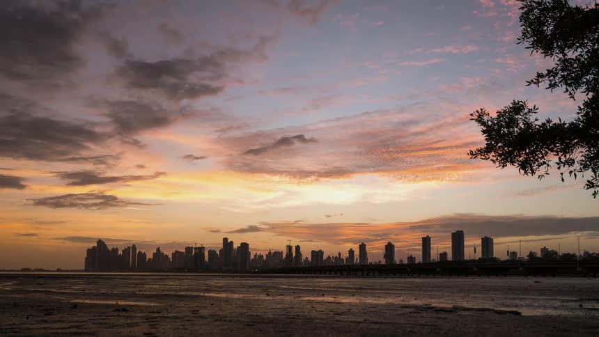 Clouds are drifting over the tops of skyscrapers in a city at dusk
