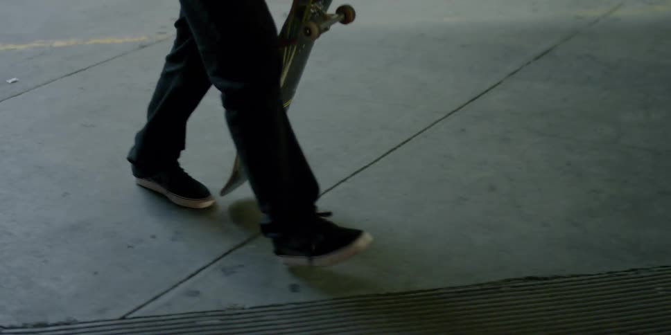 Person skates on a skateboard on a sidewalk in the evening