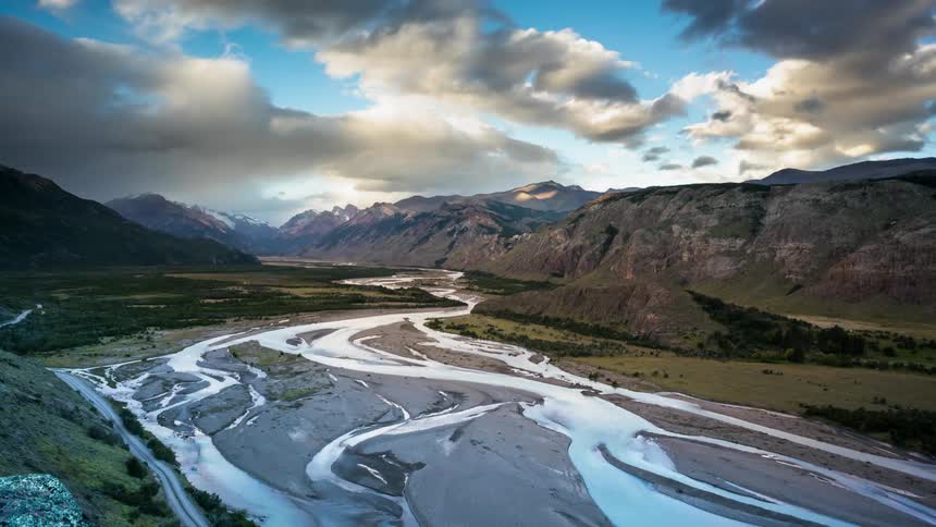 Storm clouds are passing over a riverbed in a mountain valley during the day