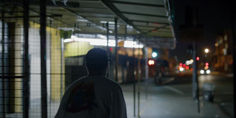 A teenager is riding a skateboard on a city sidewalk at night