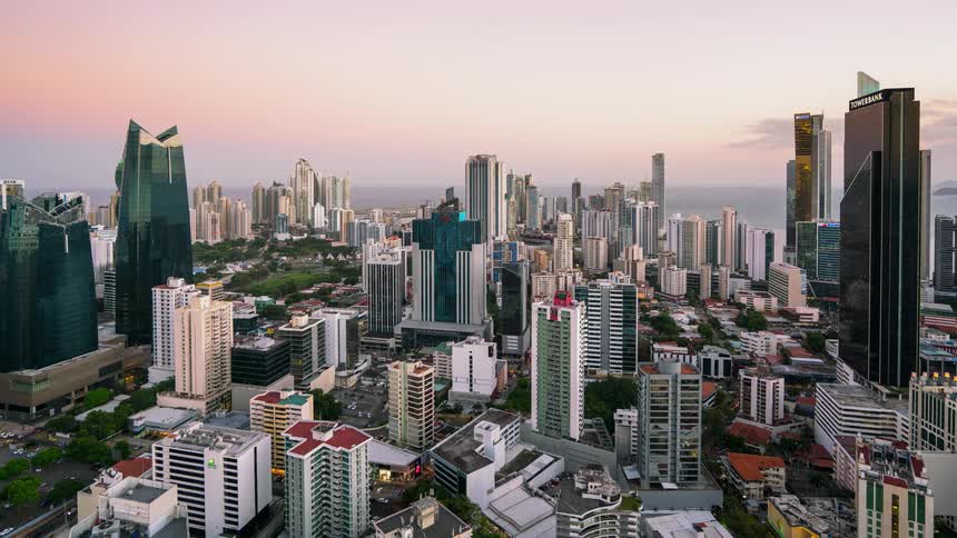 Clouds drift away from a city as day turns to dusk