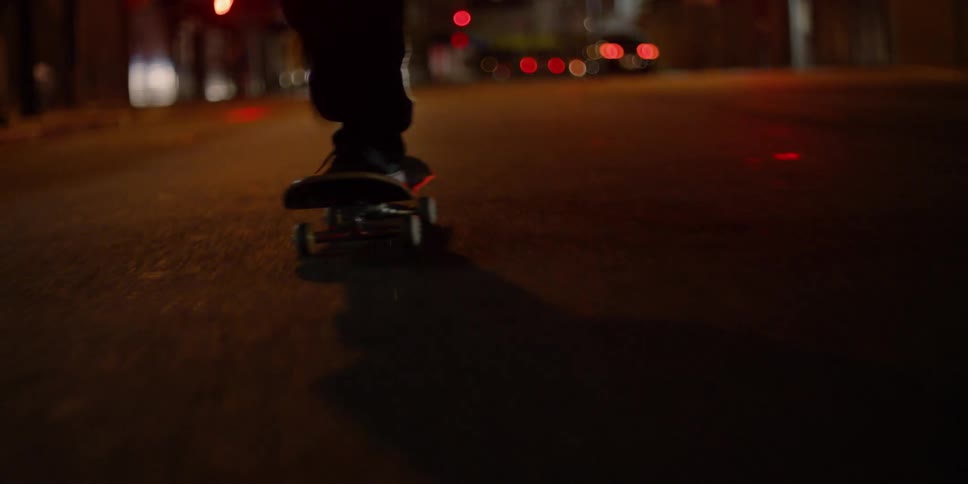 The skateboard is being kicked off by a rider at night