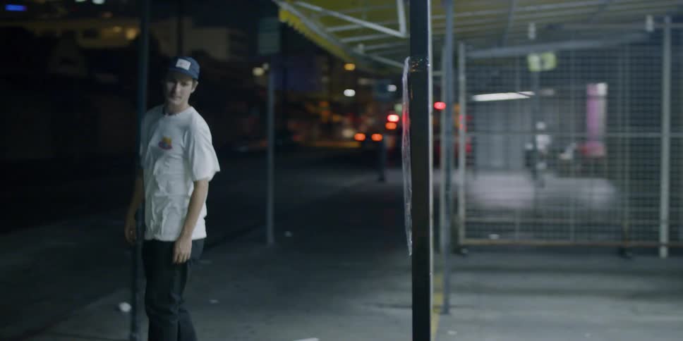 A skateboarder rides down a city sidewalk at night