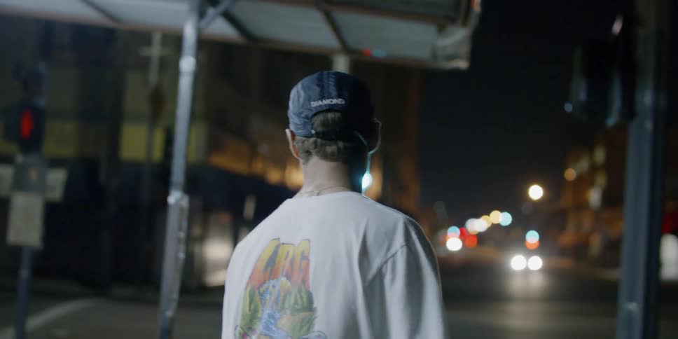 A teenager is riding a skateboard on a city sidewalk at night