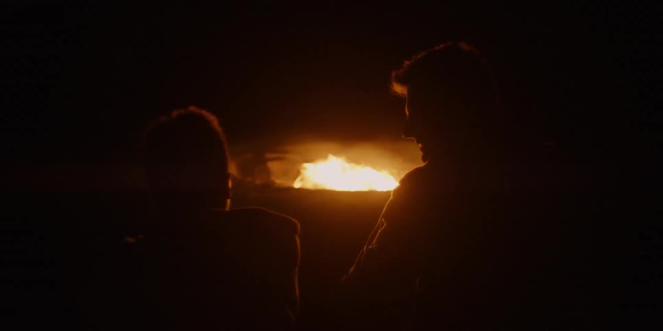 People talk by the fire at night