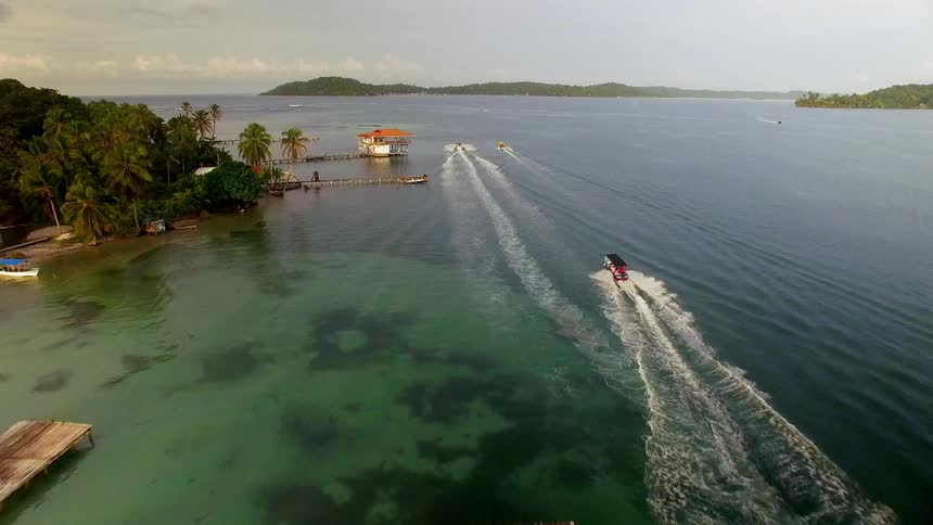 Boats speed past huts in a coastal village in Bocas del Toro
