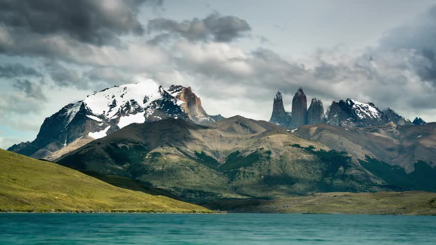 Clouds and shadow pass over snow capped mountains and ocean water
