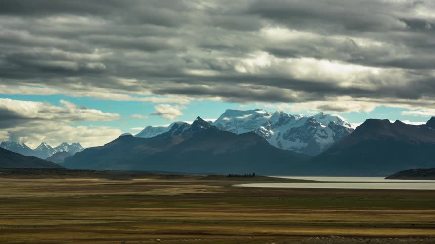 Time-lapse of clouds moving over a flat area with mountains in the distance