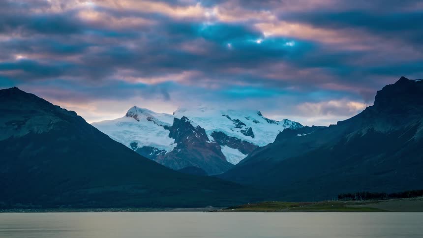 Storm clouds are forming and drifting across a mountain range at dusk