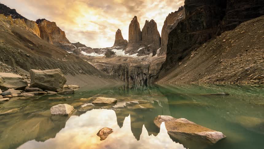 A mountain lake is reflecting passing clouds during the day