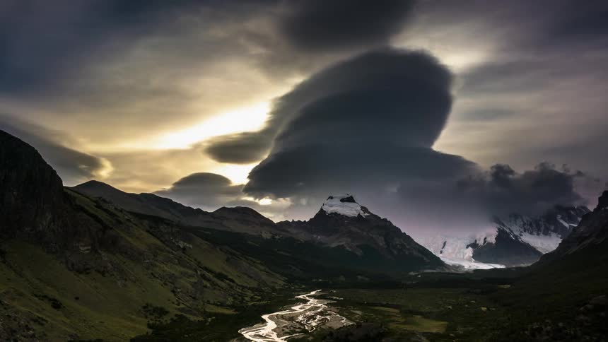 Clouds pass above snow covered mountains