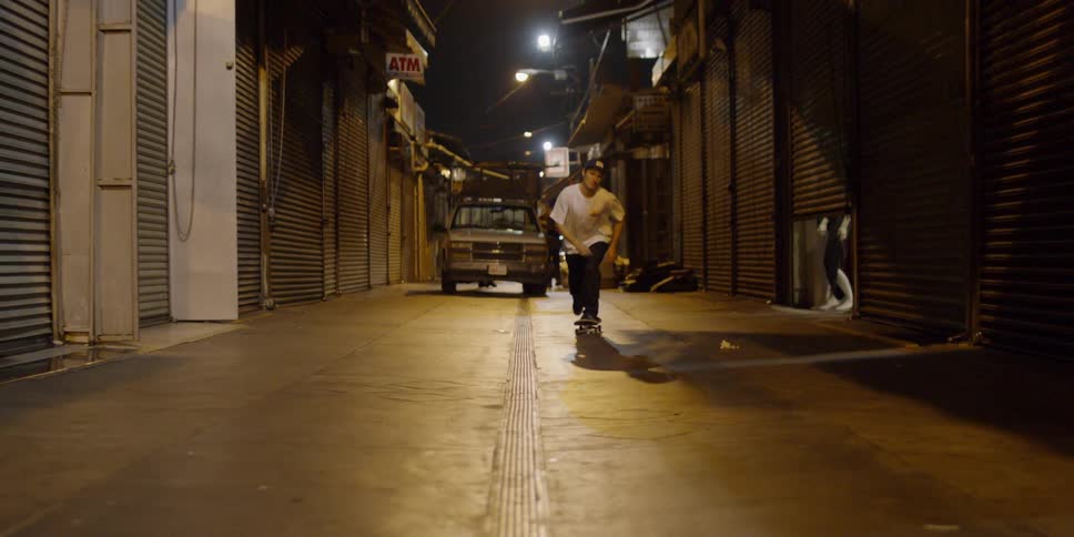 A man rides his skateboard in the dark alley