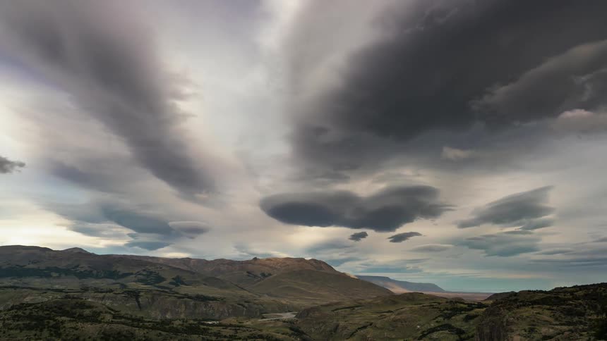 Clouds form and drift over a mountain landscape at dusk