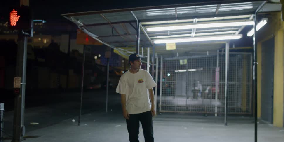 A teenager riding a skateboard is stopping at a crosswalk at night