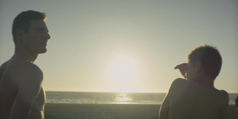 Two boys stand on the beach shore