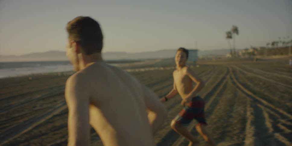Brothers laugh and push each other as they run to the ocean