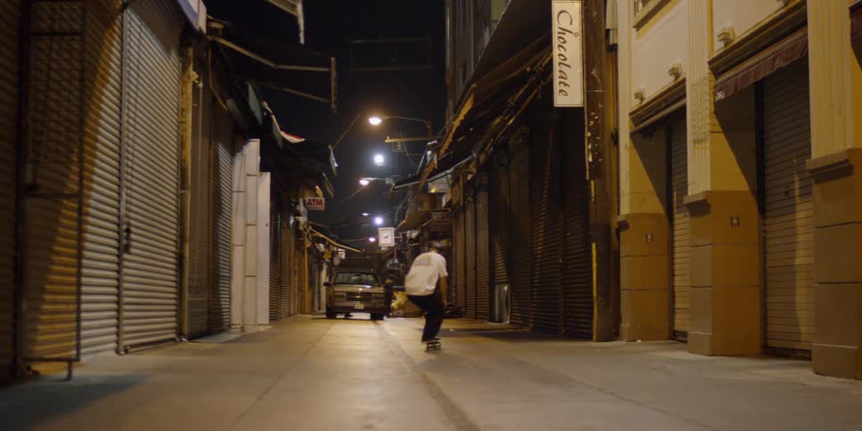 A man does a jump on the skateboard in the alley