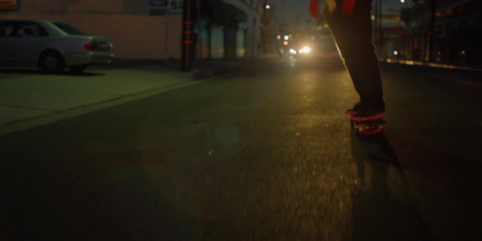 He rides the skateboard in front of the moving vehicle