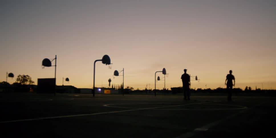 Two teenagers skate at a park at sunset