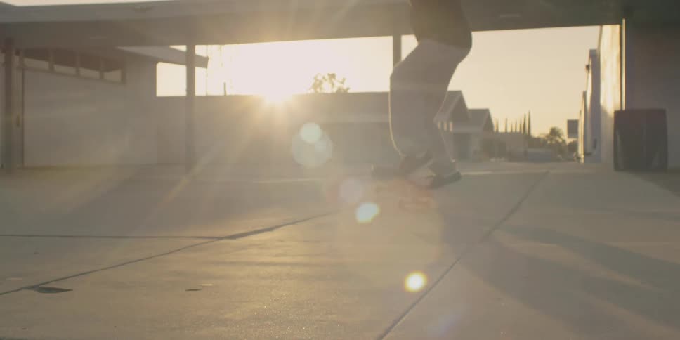 A teenager is flipping his skateboard outside at dusk