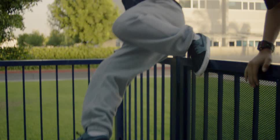 A teenager is climbing a fence during the day