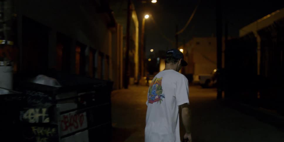 A man is riding his skateboard in the dark alley at night