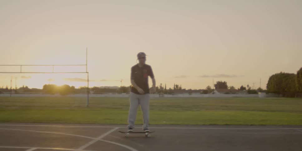 A skateboarder is kicking his board up as he rides at dusk