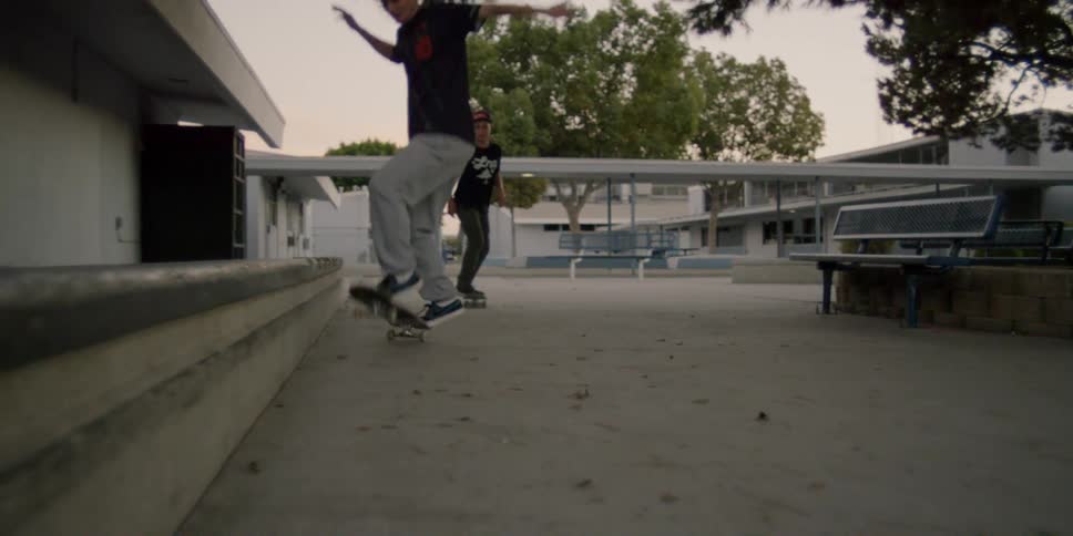 Two people ride their skateboards and one kicks it into the distance