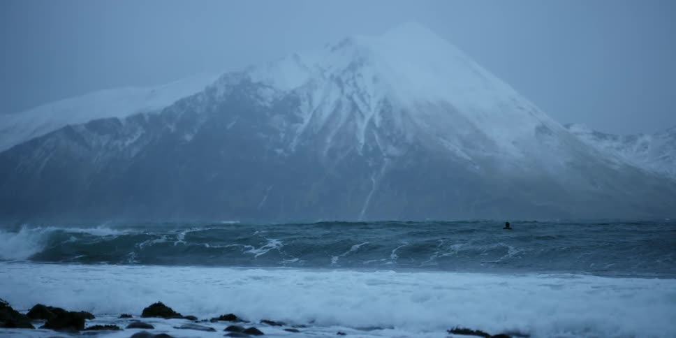 A surfer floats on waves as they crash towards the shore